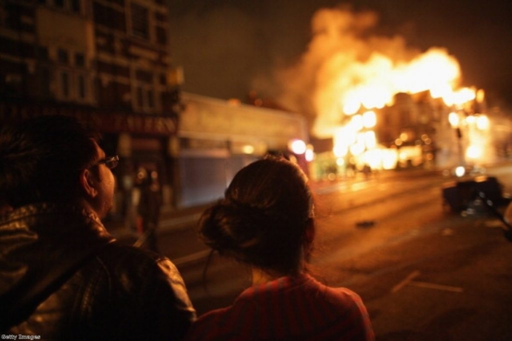 A couple watch flames rise during the disorder last week.