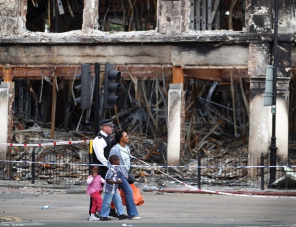 Police survey the damage after another night of rioting and looting on the streets of London