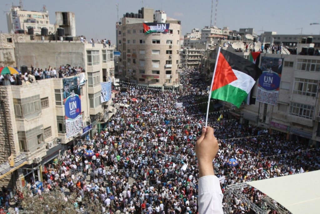 A Palestinian flag waves over the West Bank city of Ramalla yesterday as thousands gather to press for recognition at the UN.