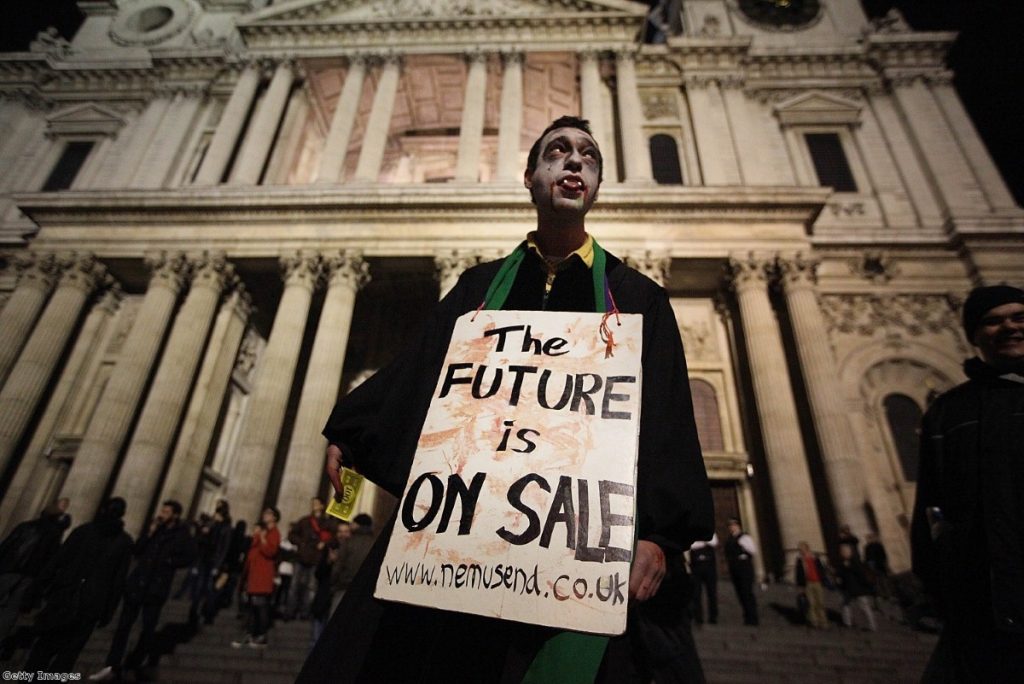 A protestor dressed as a Zombie carries a placard in front of St Paul's