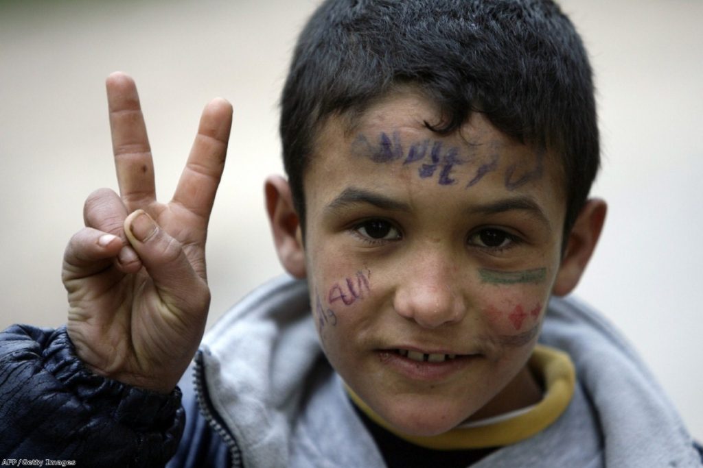 A young Syrian refugee fleeing violence in Homs flashes the 