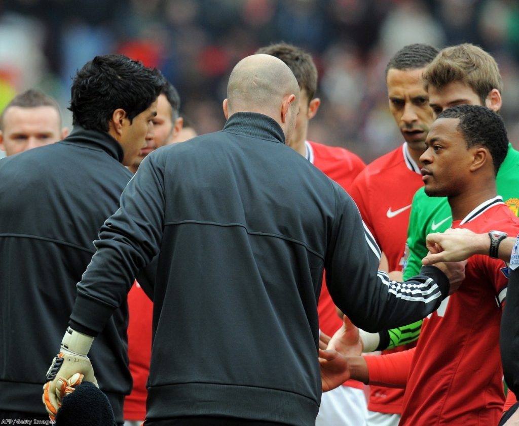 Rio Ferdinand looks disgusted as Suarez fails to shake Evra