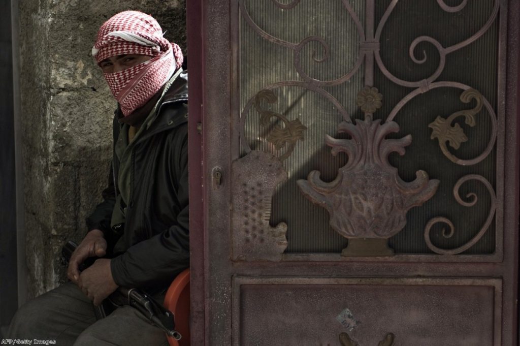 A Free Syria army member sits guard at a gate during the funeral of a man who was killed by a shrapnel in Qusayr earlier this year.