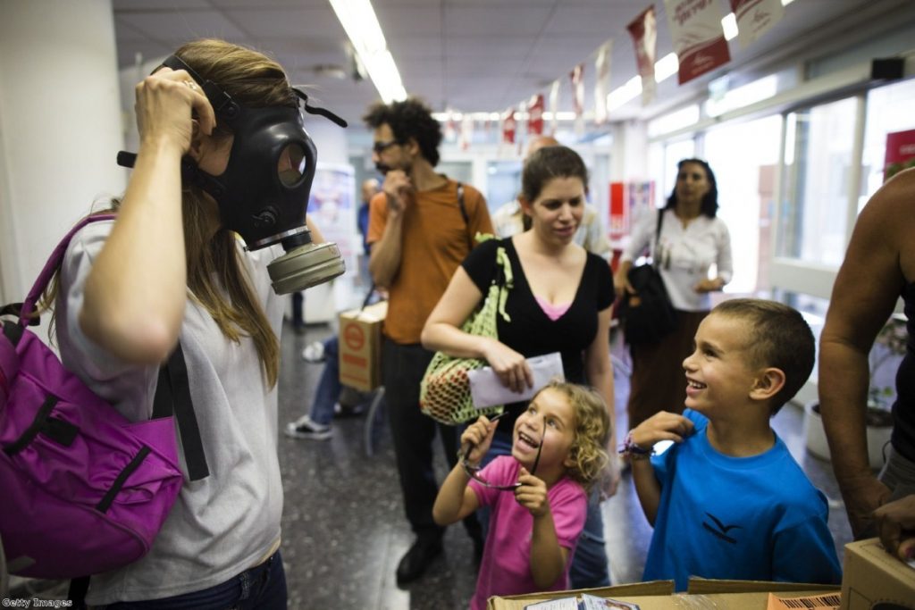 An Israeli woman shows her children how to put on a gas mask yesterday  in Tel Aviv, amid tensions over possible military action in Syria  