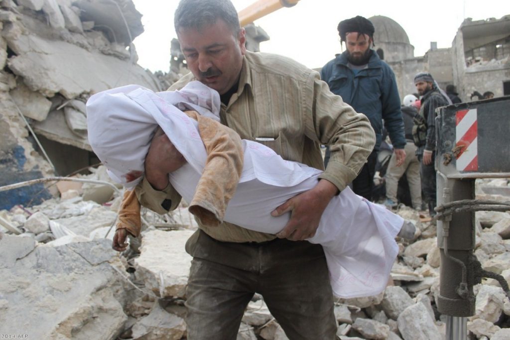 A Syrian man carries a body out of the rubble following air raids by government forces  