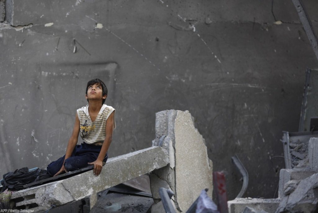 A Palestinian boy sits on the rubble of a destroyed building following an Israeli air strike in the center of Gaza City on July 22, 2014