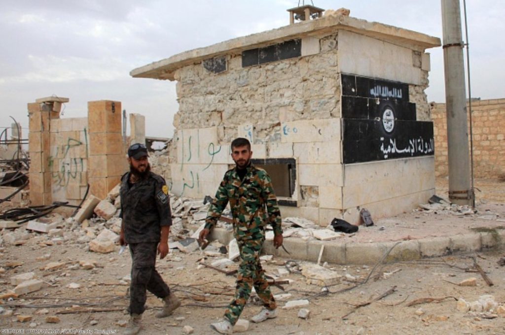 Syrian government forces walk past a building bearing an image on the wall with Islamic writing and reading in Arabic the 