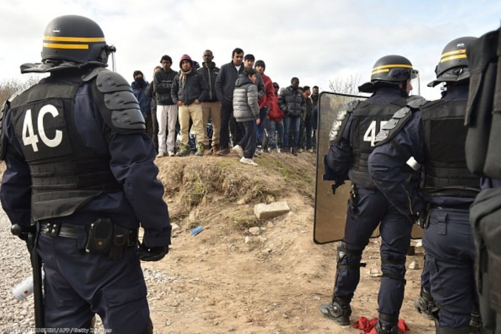 Anti-riot police face migrants during the dismantling of half of the 