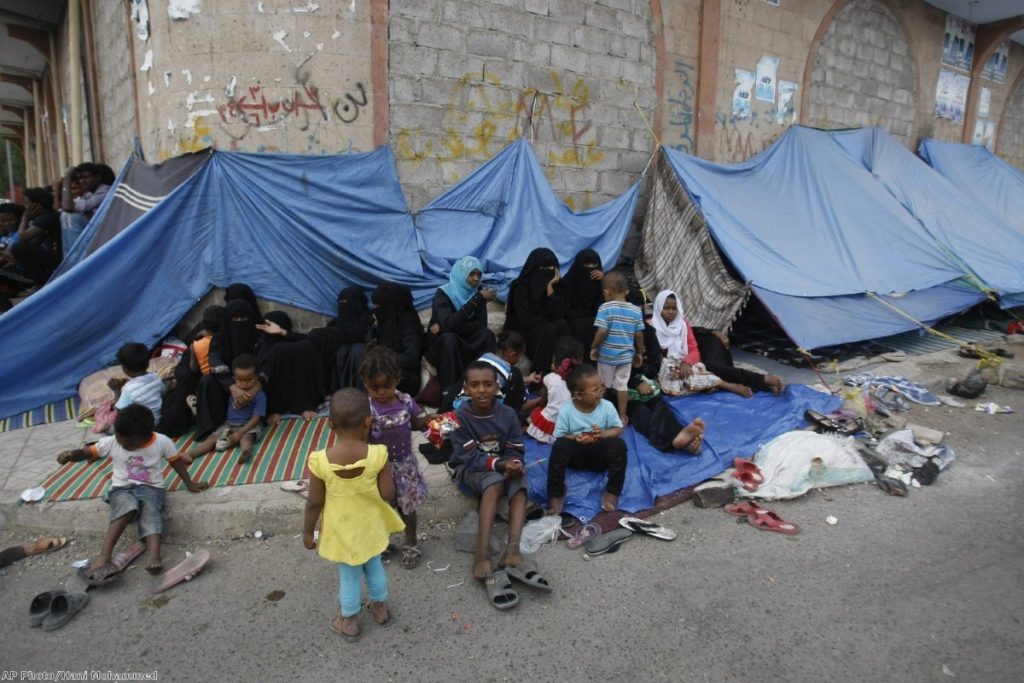 Eritrean female asylum seekers sit along with their children on the sidewalk in Yemen 