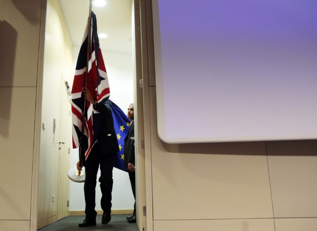 Members of protocol prepare to put up British and EU flags prior to a conference between Michel Barnier and David Davis last month 