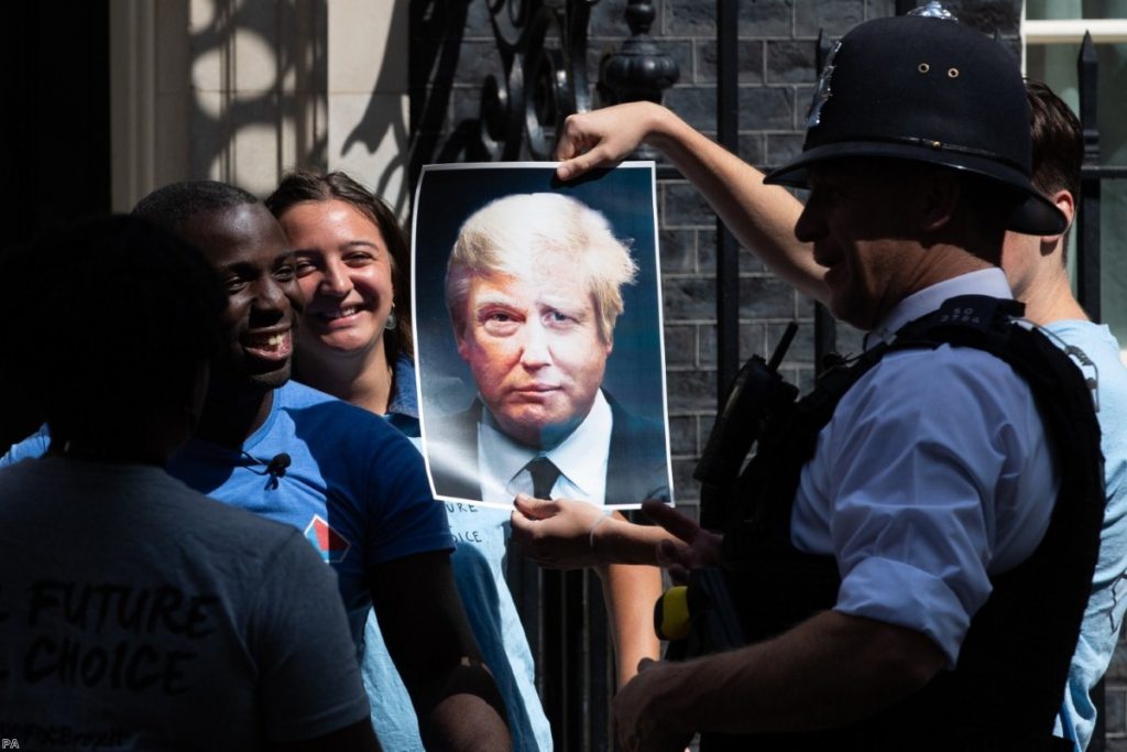 Campaigners for the youth group Ofoc hold up a poster melding Johnson and Trump