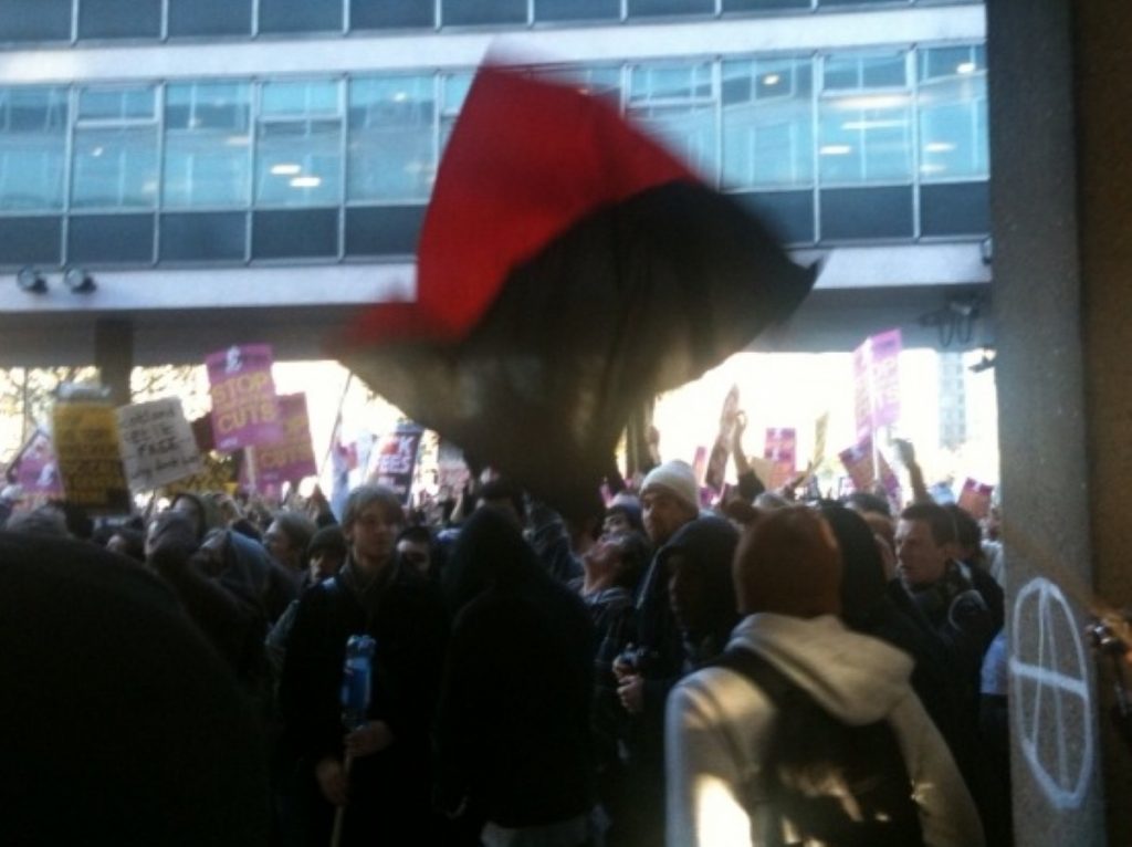 An Anarcho-Communist flag flies above the student protest in Millbank on Wednesday