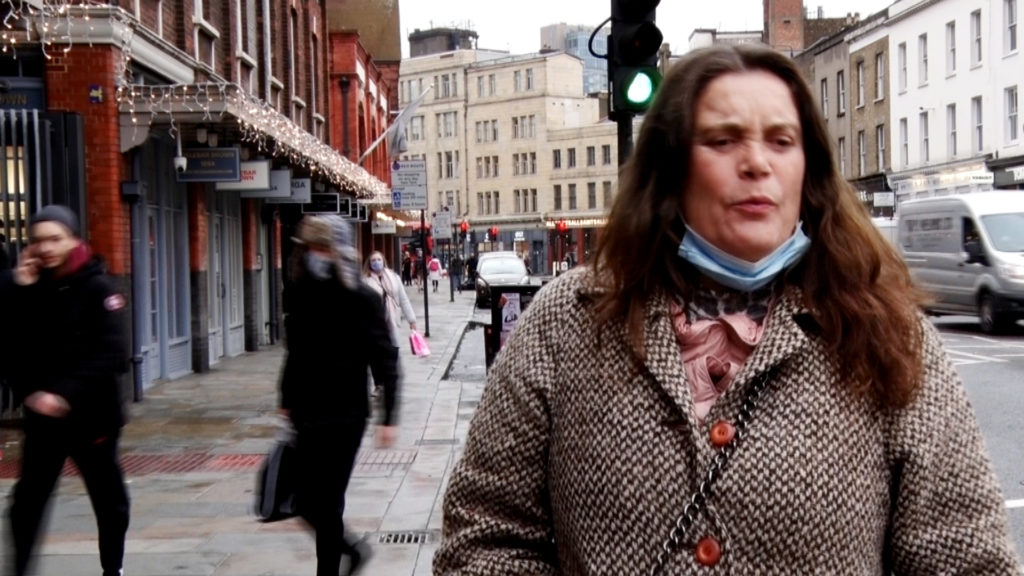 A woman thinking with lips pursed on a street in London